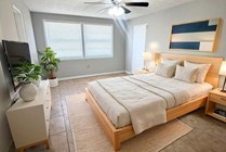 Bright and inviting bedroom with a modern design, featuring a cozy wooden bed, contemporary artwork, and serene natural lighting.