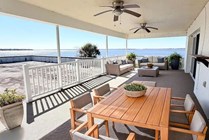 Spacious waterfront patio with elegant outdoor furniture, offering stunning views and relaxation under ceiling fans.