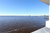Breathtaking waterfront view from balcony, showcasing expansive blue waters and clear skies, perfect for relaxation.