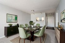 Elegant dining room with a modern green theme, featuring a stylish dark wood table, matching chairs, minimalist decor, and contemporary artwork.