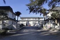 Charming apartment complex featuring elegant architecture and landscaped surroundings, with for rent signs visible at the entrance.