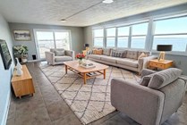 Bright and inviting living room with panoramic water views, featuring comfortable seating, elegant decor, and ample natural light.