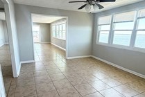 Bright and airy living space featuring large windows with stunning water views, tiled flooring, and a ceiling fan for comfort.