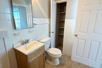 Bright and inviting bathroom featuring modern fixtures, spacious vanity, and convenient open shelving for storage.