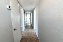 Bright, spacious hallway with modern tile flooring and sleek white walls leading to cozy rooms.