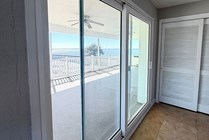 Bright interior featuring large sliding glass doors opening to a spacious balcony with stunning ocean views.